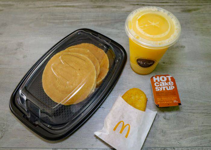 A serving of McDonald's hotcakes, bought alongside a hash brown and orange juice.